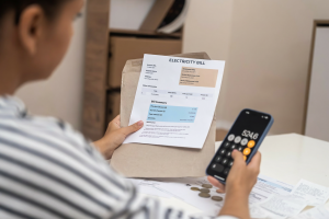 Person reviewing a high electricity bill while calculating costs on a smartphone, highlighting rising energy expenses in Australia.