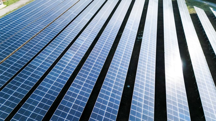 Large scale solar farm installation with rows of high efficiency solar panels generating renewable energy.
